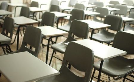 Photo of empty single grey desks in a classroom. Photo by MChe Lee on Unsplash