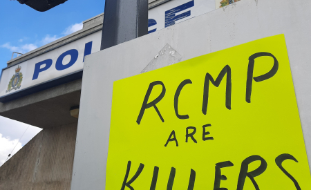 Poster saying RCMP Are Killers, on a post in front of an RCMP detachment.