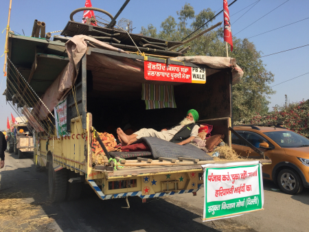 A farmer resting at the back of his truck as he heads home. Photo: Vandana K