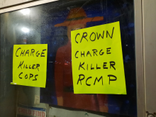 Posters on RCMP window saying charge killer cops and crown charge killer RCMP